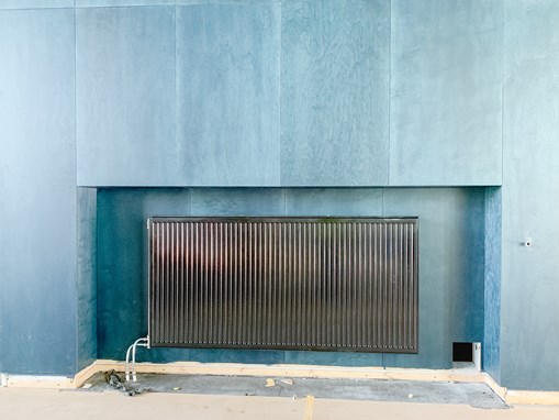 Svart radiator som är placerad vid en blågrön vägg